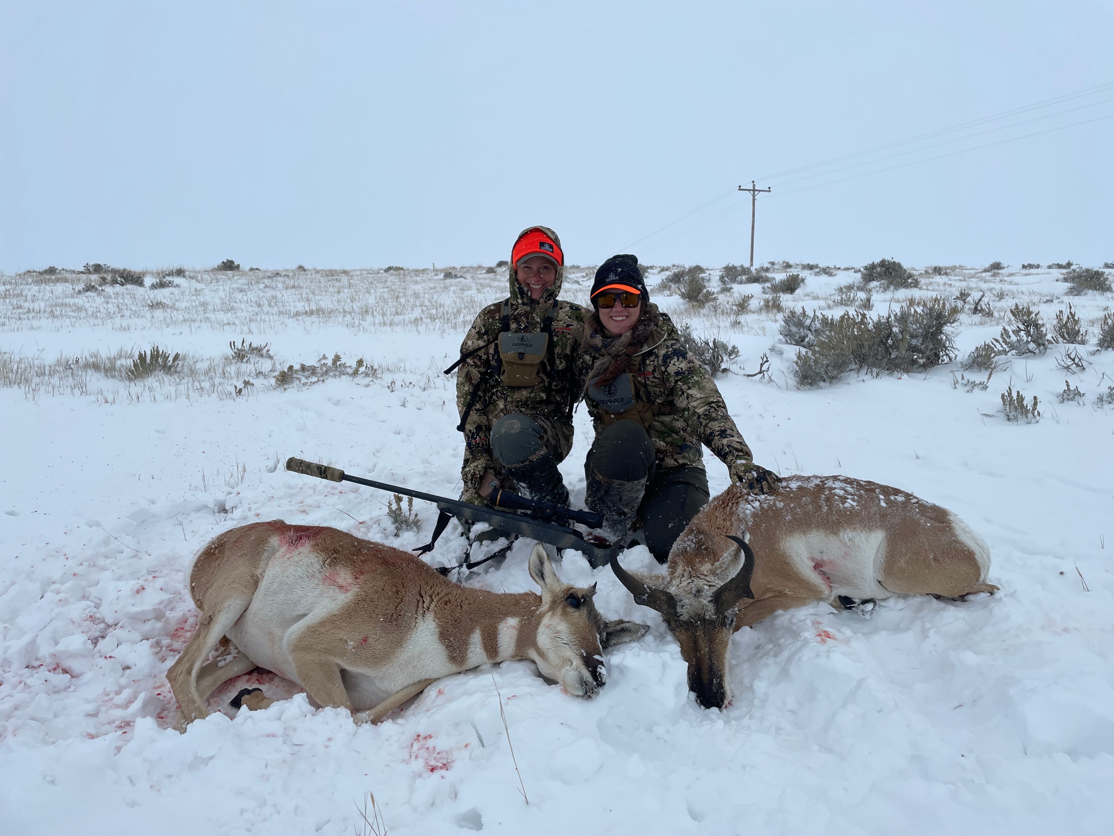 Two hunters with two harvested antelope in deep snow