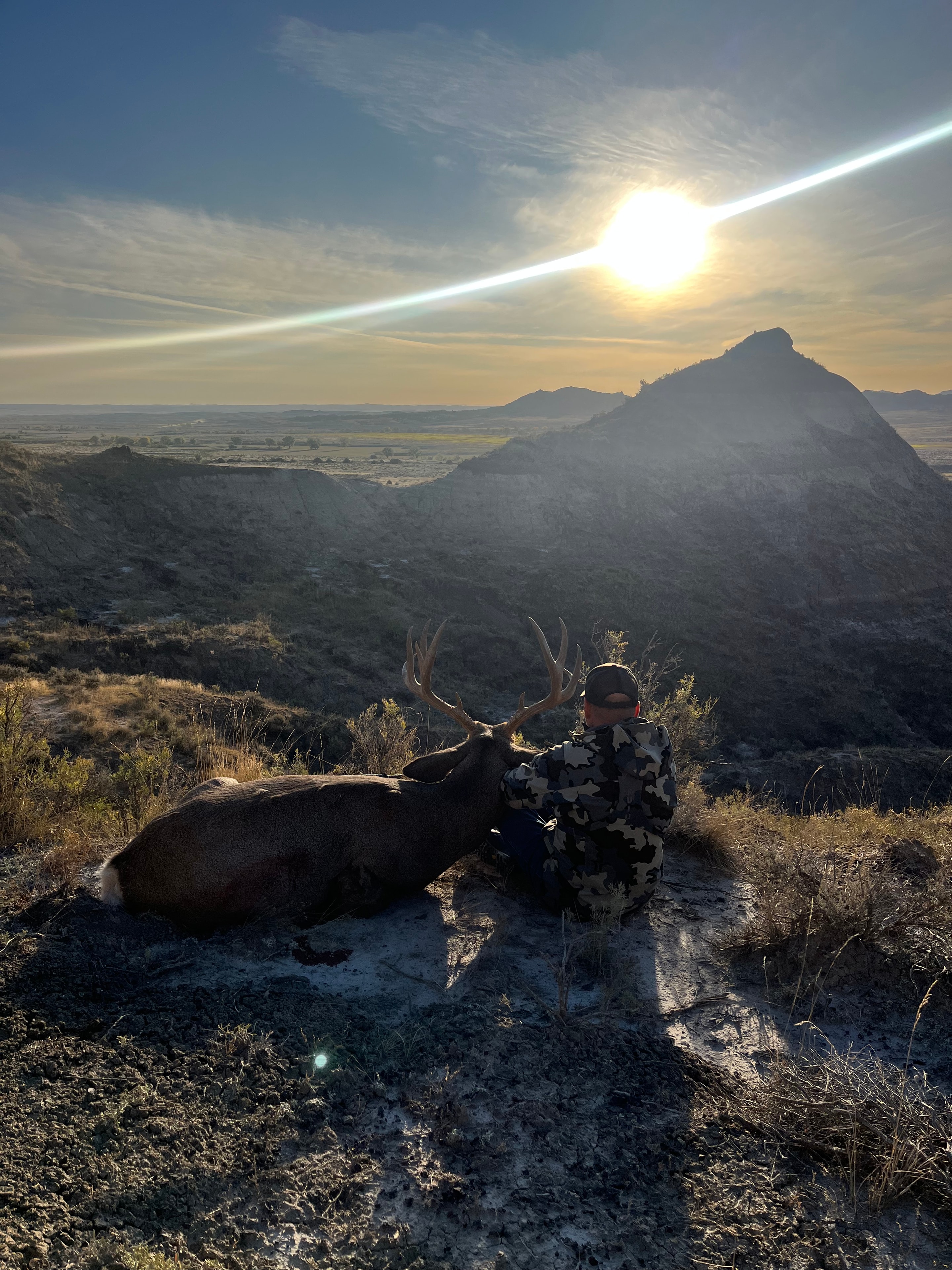 Hunter with mule deer buck at sunset in canyon country