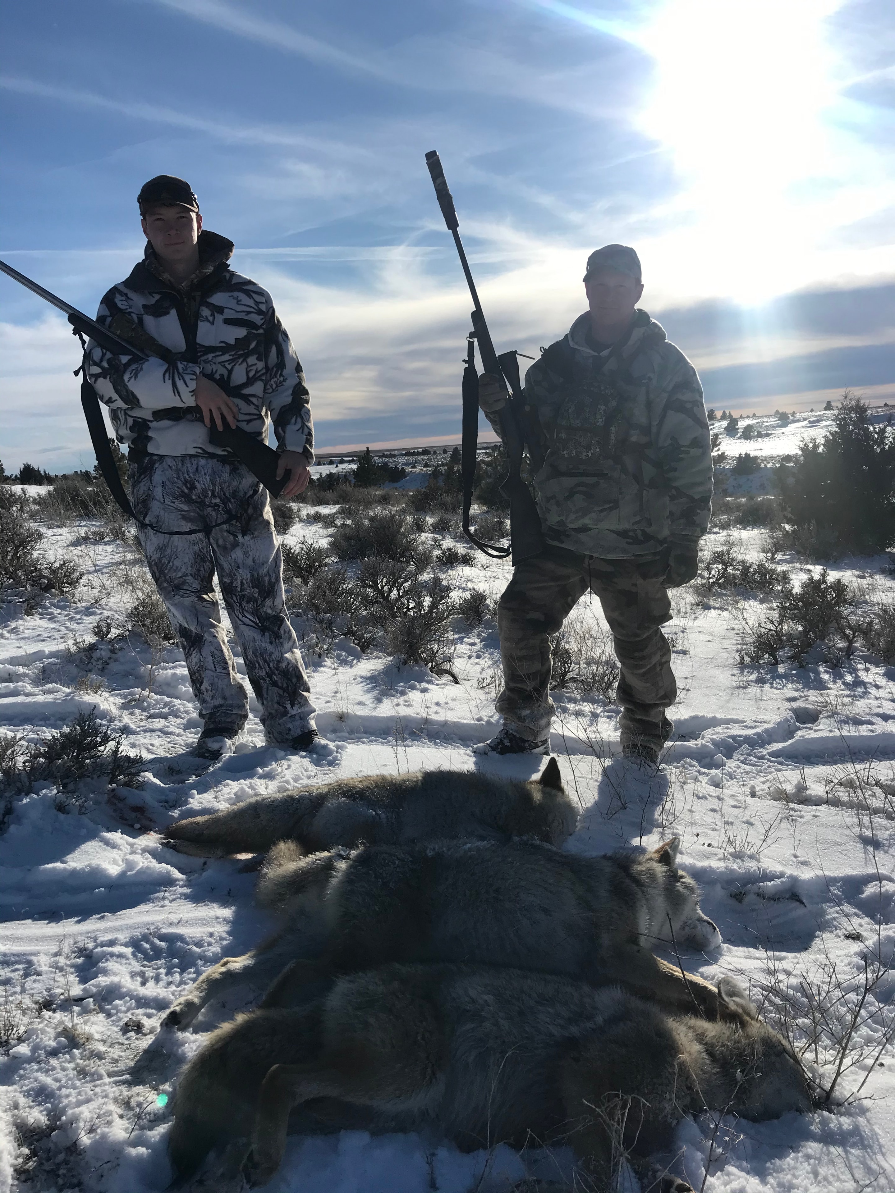 Two hunters with harvested wolf in deep snow