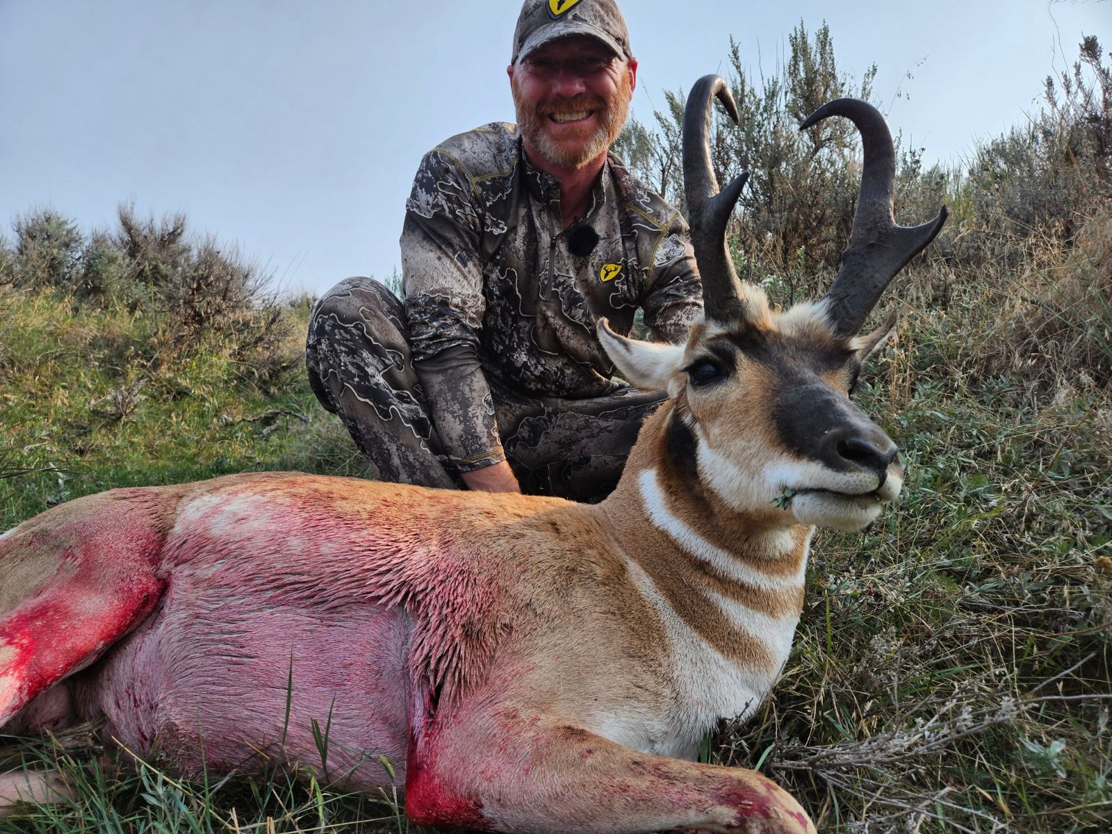 Hunter with harvested antelope buck in open prairie
